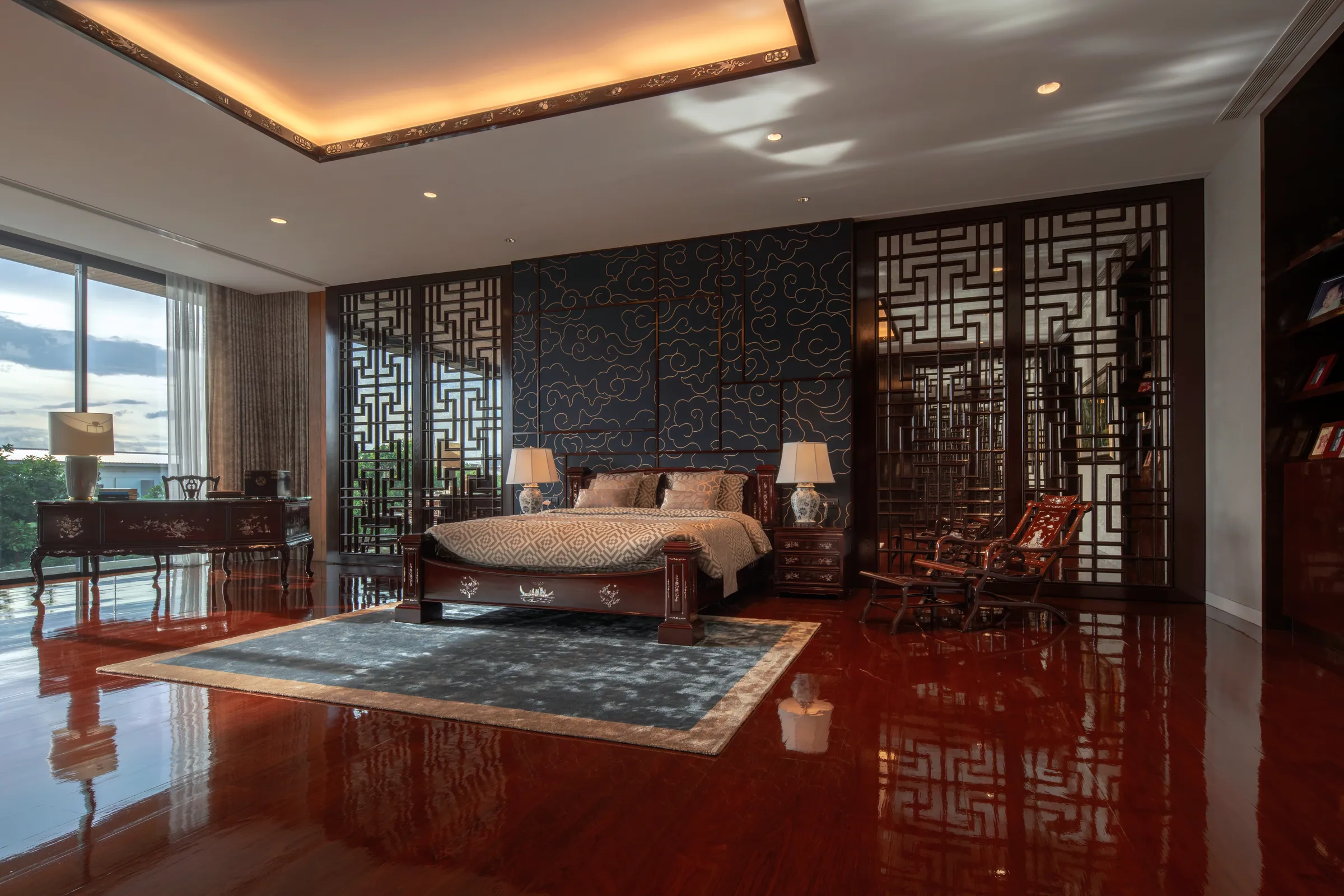 Bedroom 1 at Khon Kaen Residence — polished burgundy lacquer floor, dark wood screens, warm cove lighting.