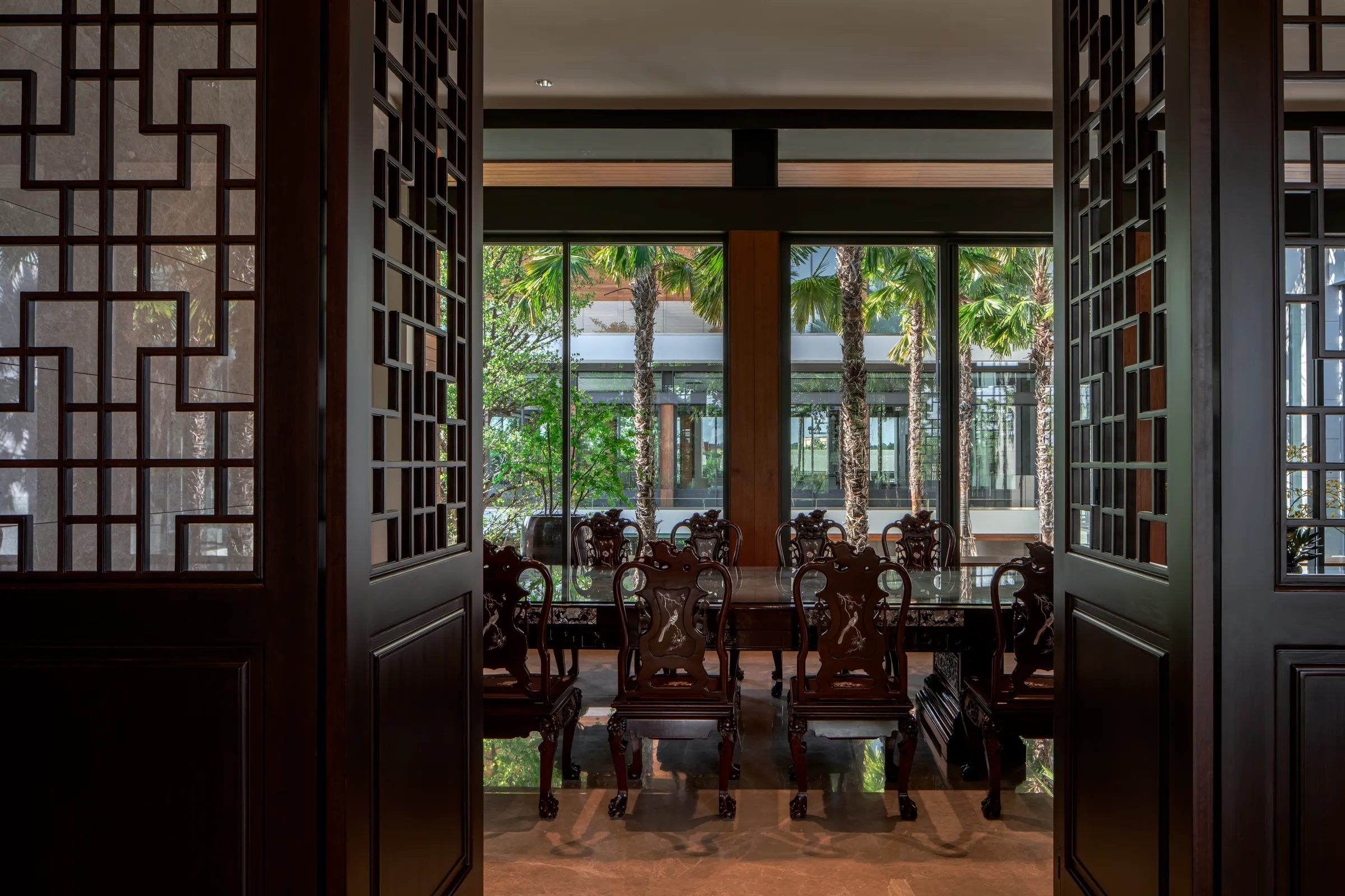 Dining room 2 — narrow ceremonial view through dark wood screens lined with carved Ming-style chairs.