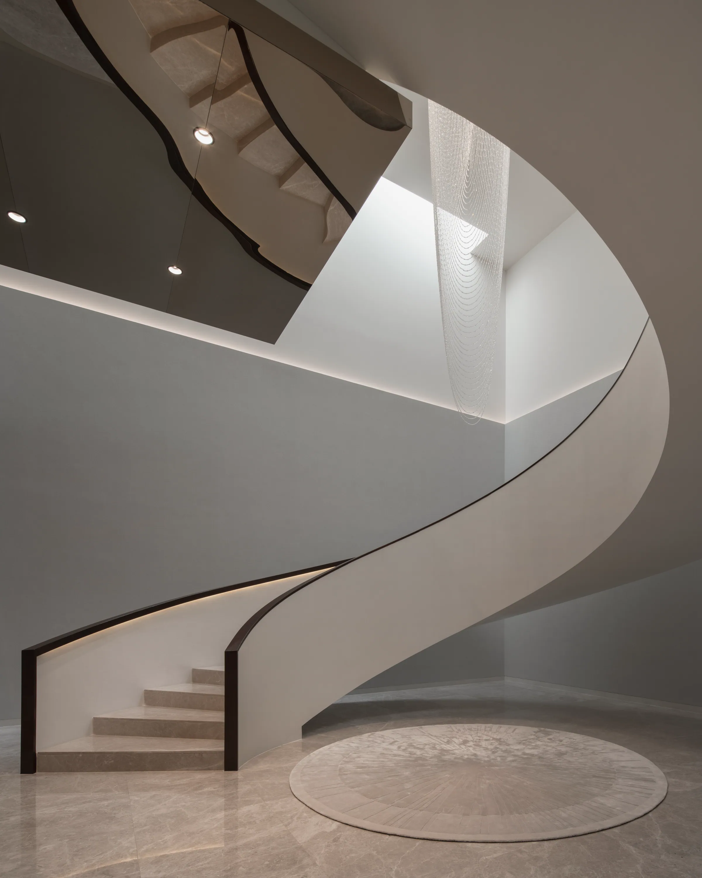 Curved staircase at Khon Kaen Residence, soft grey-white treads with black metal handrail.