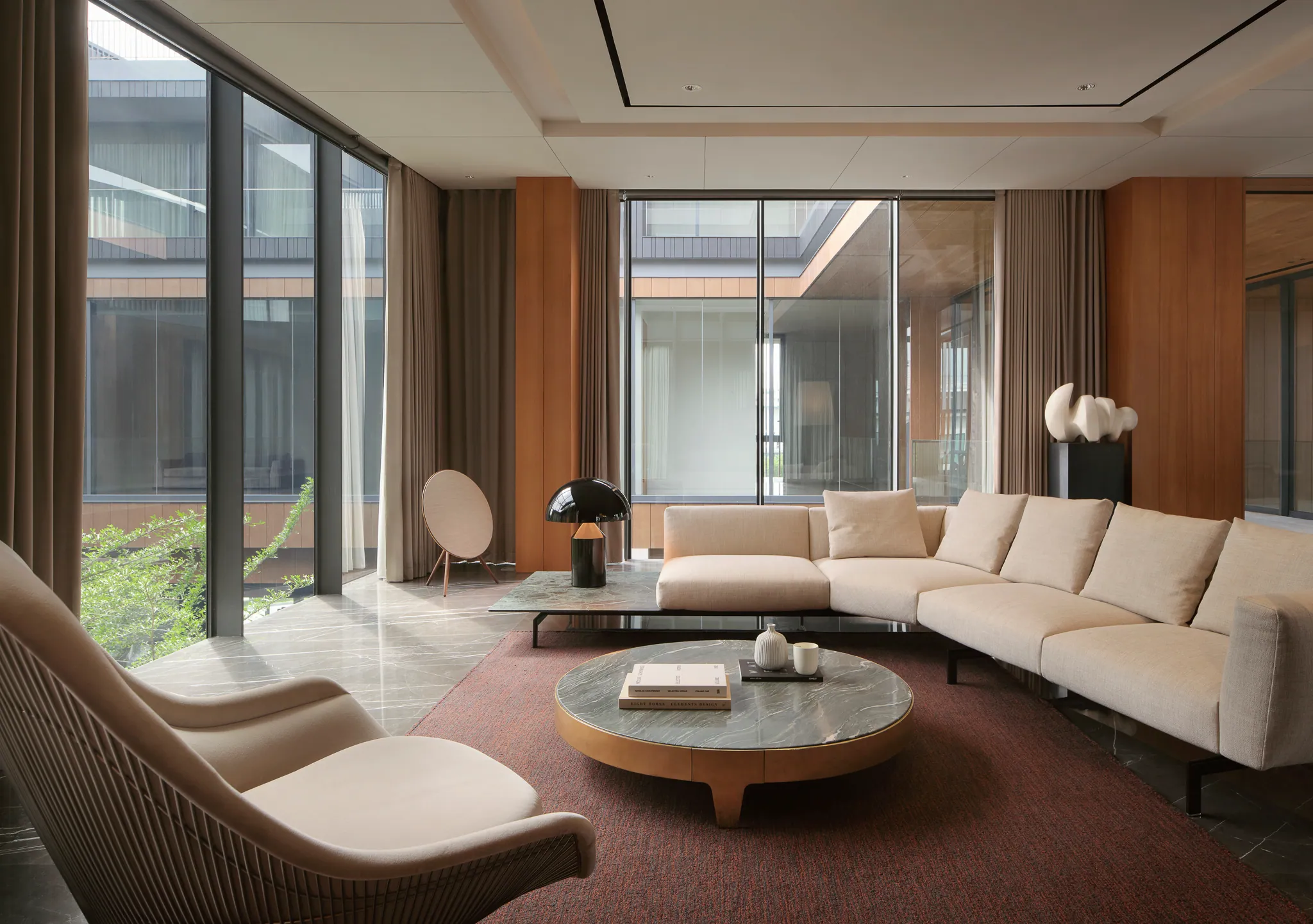Second-floor living lounge at Black Box Project — soft cream-and-terracotta palette, low cream sofa, round wood side table.