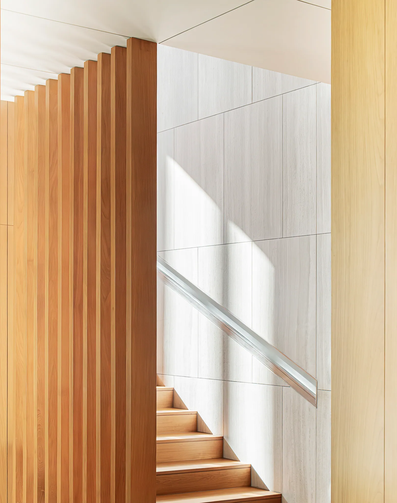 Slatted vertical wood at the staircase landing of Black Box Project, daylight catching the rhythm.