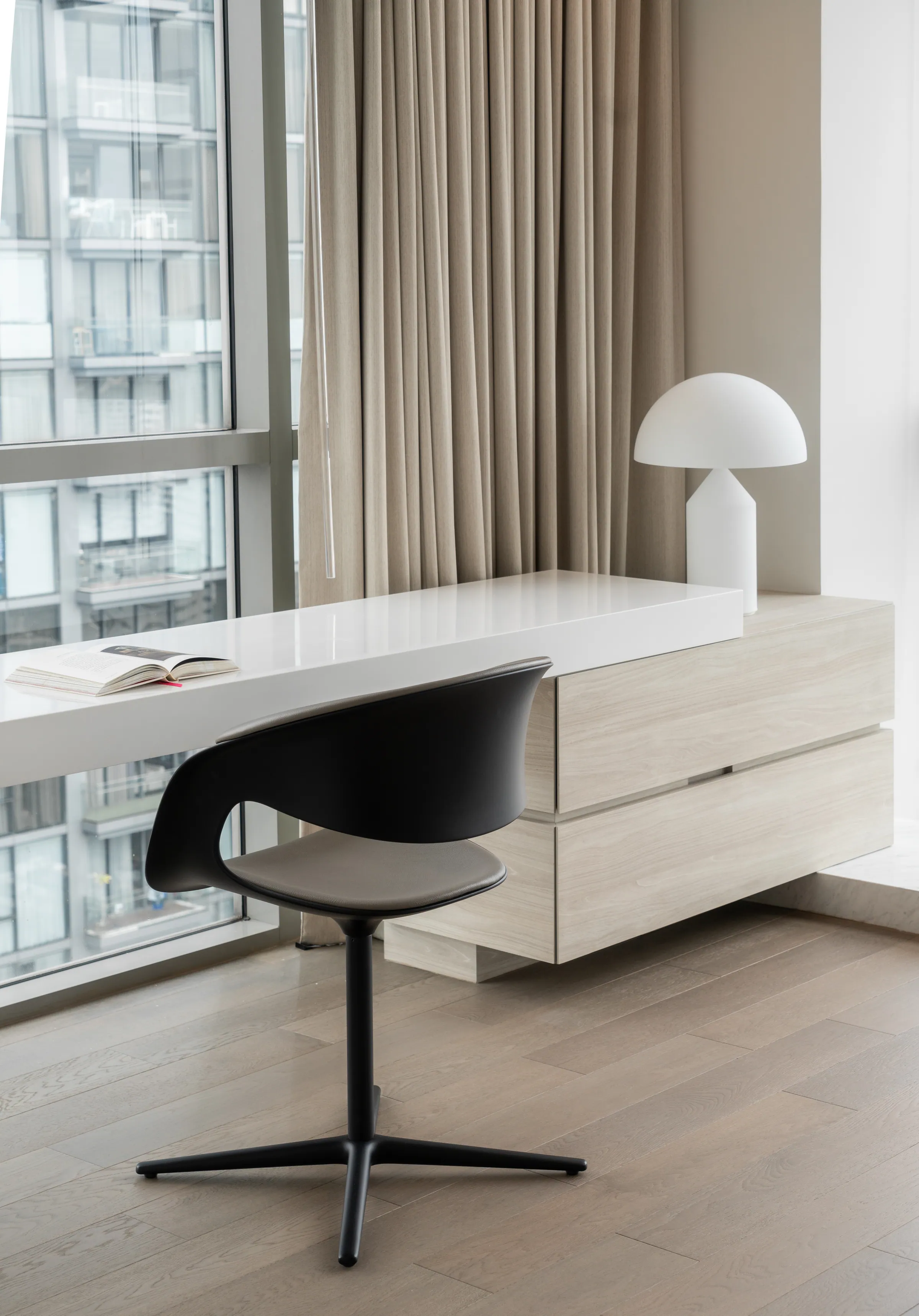 Guest bedroom desk at Madison Penthouse — white lacquer console at the window with a black moulded chair and a domed table lamp.