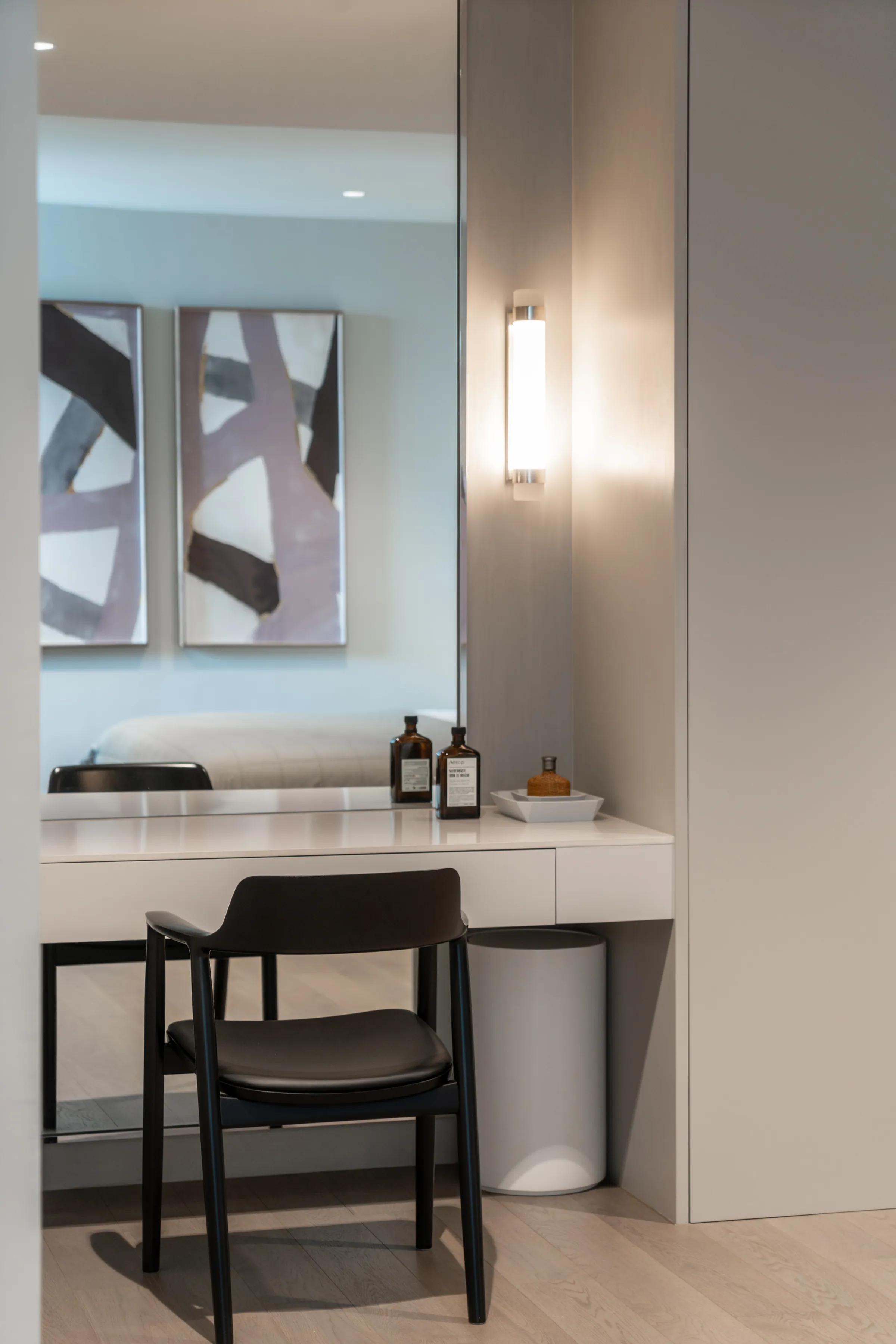 Dressing table in the third bedroom at Madison Penthouse — mirrored vanity with amber apothecary bottles and a linear wall sconce.