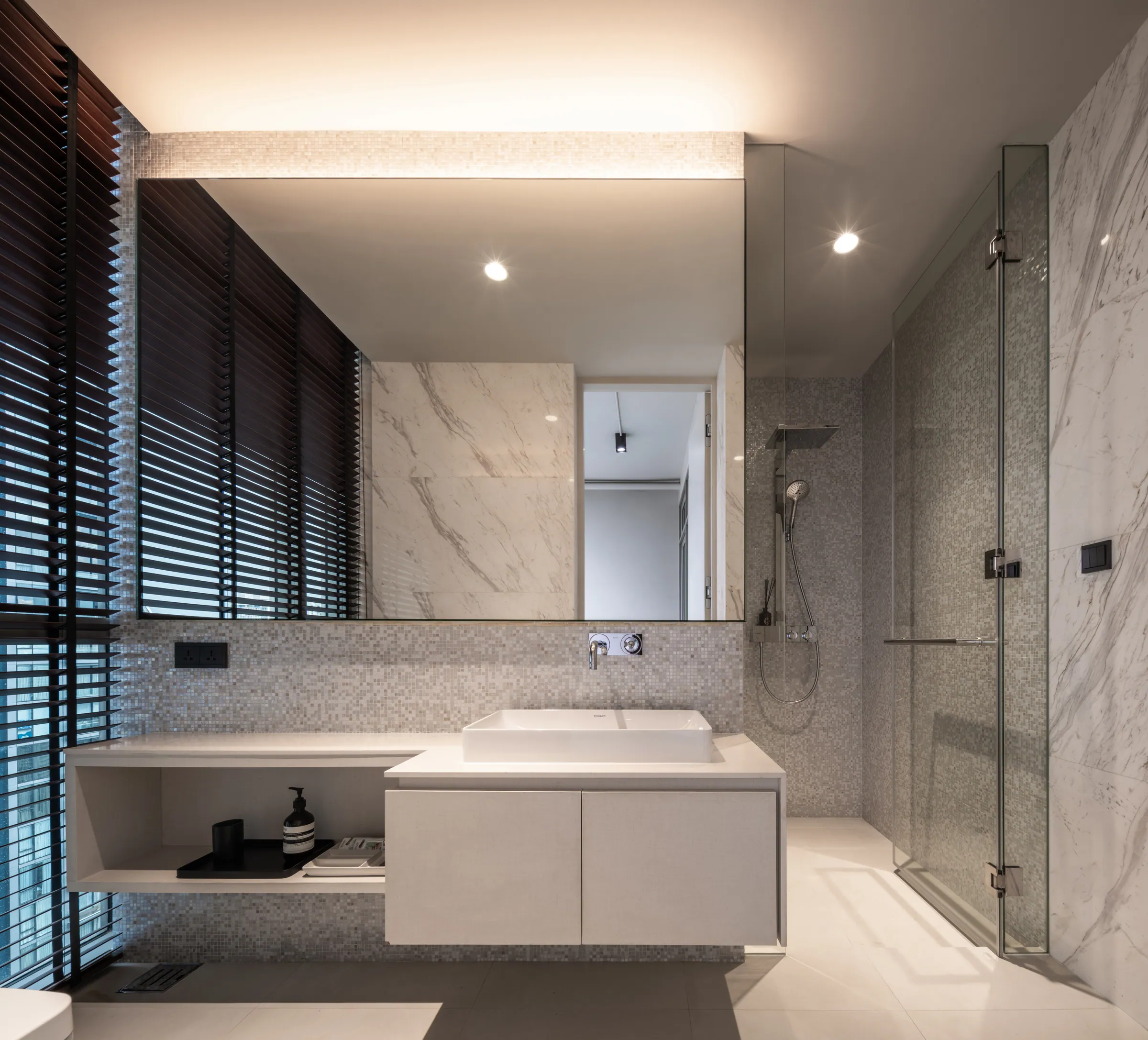 Third bathroom at Madison Penthouse — white marble slab, timber blinds, a walk-in glass shower and a floating vanity.