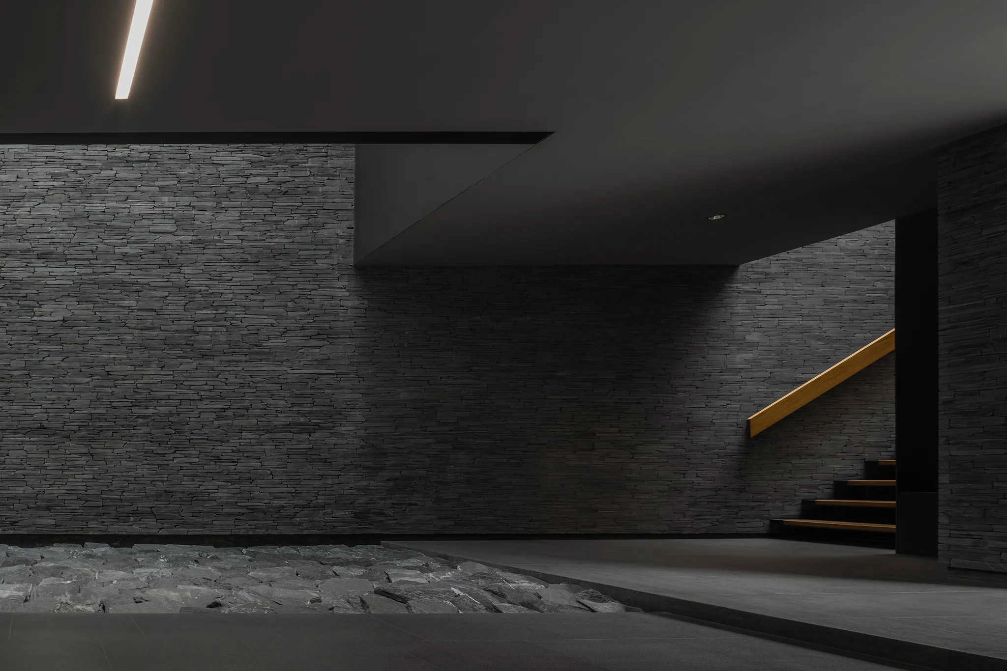 Garage at Water House — multiple luxury vehicles under museum-quality lighting, stepped entry, dark minimalist showroom.