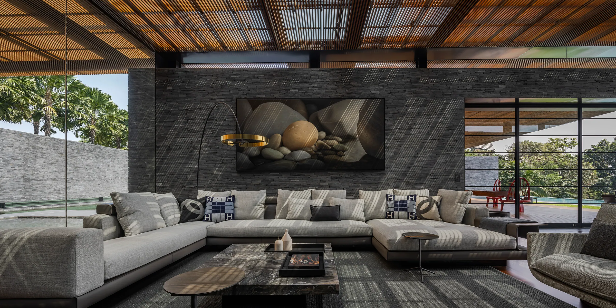 Sunken living room at Water House — grey U-shaped sectional, rust-oxide abstract artwork as focal point.