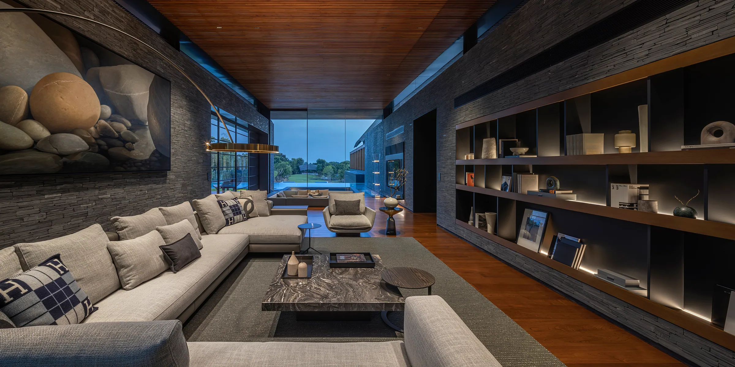 Evening entertainment lounge at Water House — amber-lit shelves, pool view through glass.