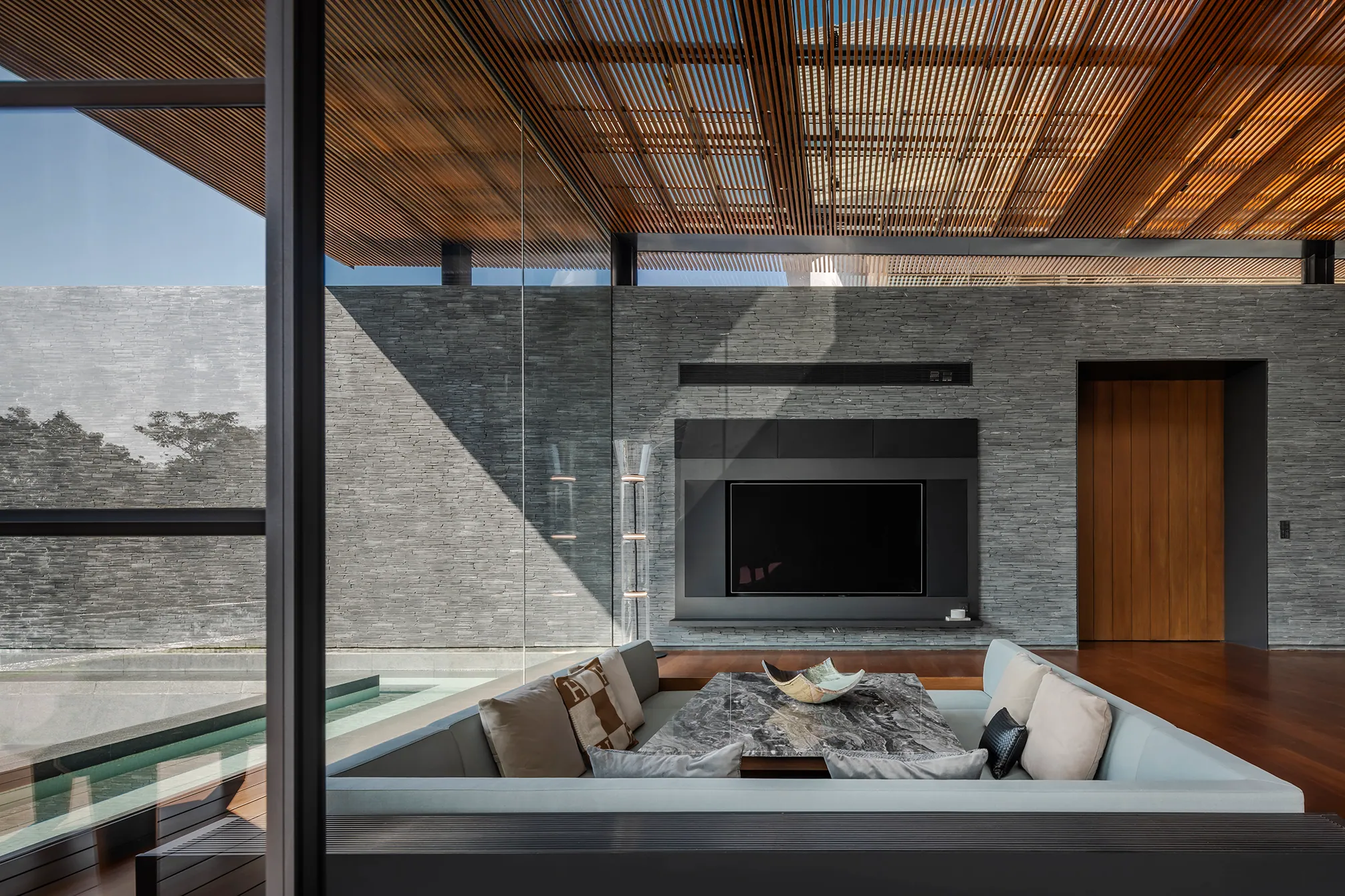 Sunken lounge with slate water feature, wood slatted ceiling, mountain view.