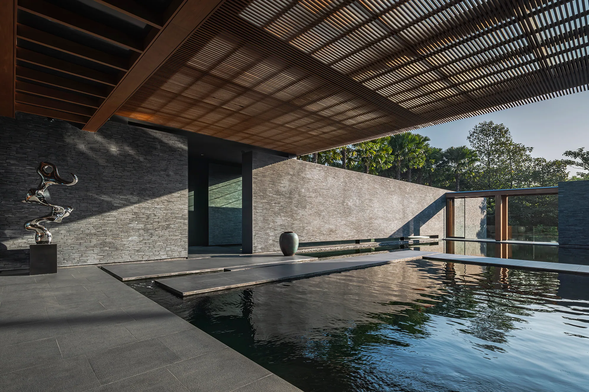 Exterior pool deck with wood pergola and meditation seating.