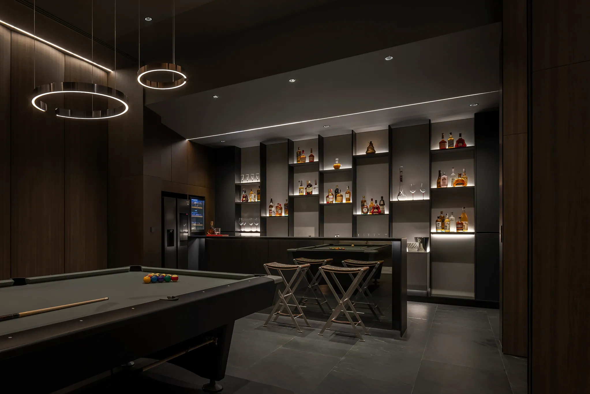 Billiards lounge at Water House — full bar with backlit liquor display, circular pendant lights, championship table.